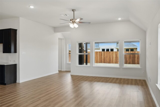 unfurnished living room featuring visible vents, lofted ceiling, light wood-style floors, and baseboards