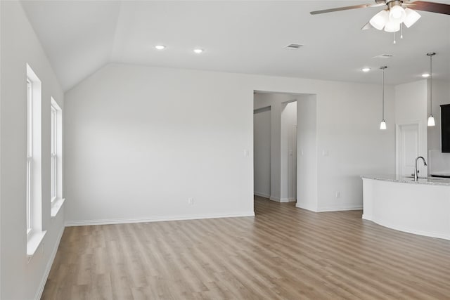 unfurnished living room with baseboards, visible vents, lofted ceiling, ceiling fan, and light wood-type flooring