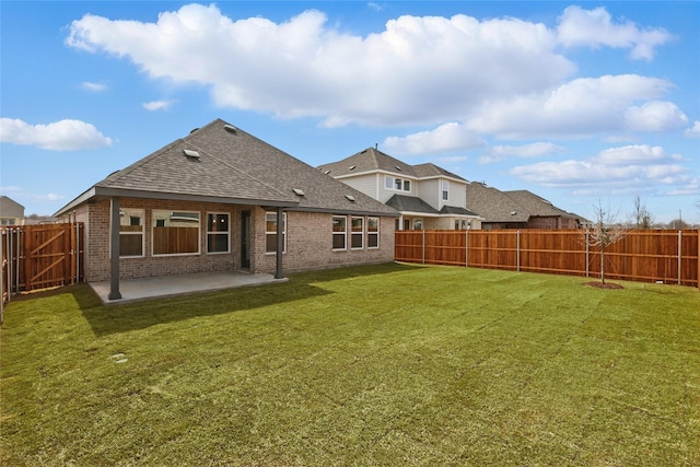 back of house with a yard, a patio area, brick siding, and a fenced backyard