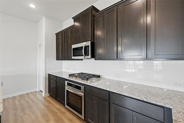 kitchen featuring backsplash, stainless steel appliances, light wood-style floors, light stone countertops, and dark brown cabinets