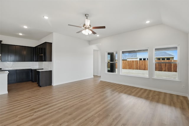 unfurnished living room featuring baseboards, vaulted ceiling, recessed lighting, light wood-style flooring, and a ceiling fan