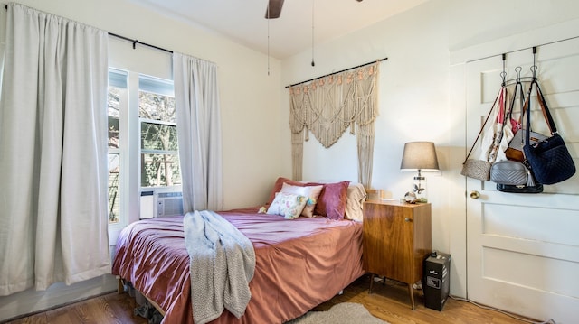 bedroom featuring ceiling fan, cooling unit, and hardwood / wood-style flooring