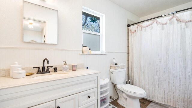 bathroom with curtained shower, toilet, and vanity