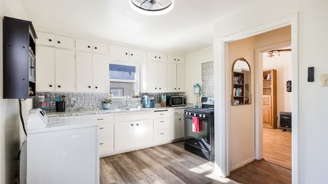 kitchen featuring white cabinetry, decorative backsplash, light wood-type flooring, black range with gas cooktop, and sink