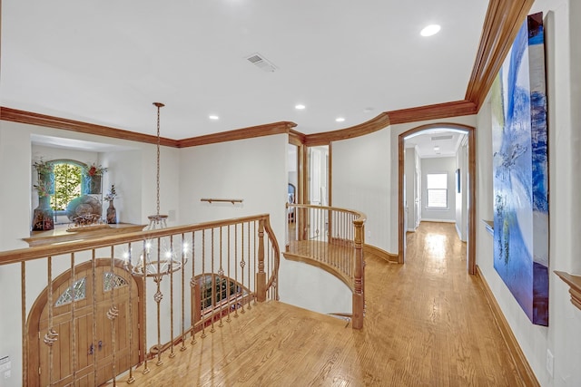 hall featuring light hardwood / wood-style floors, crown molding, and a chandelier