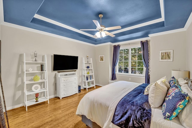 bedroom featuring ceiling fan, wood-type flooring, a tray ceiling, and ornamental molding