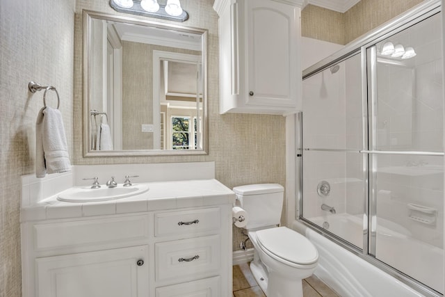 full bathroom with toilet, bath / shower combo with glass door, tile patterned flooring, ornamental molding, and vanity