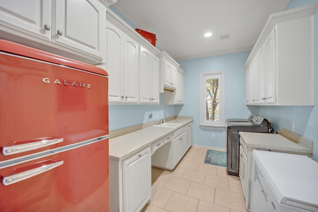 laundry area with independent washer and dryer, sink, crown molding, light tile patterned floors, and cabinets