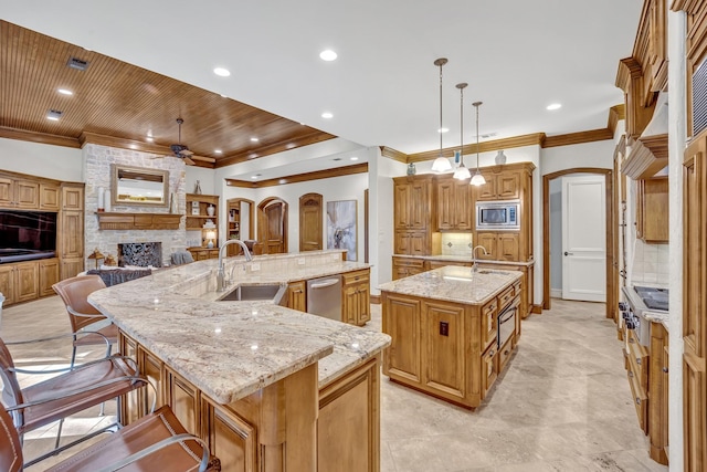 kitchen with decorative light fixtures, backsplash, a large island with sink, sink, and appliances with stainless steel finishes