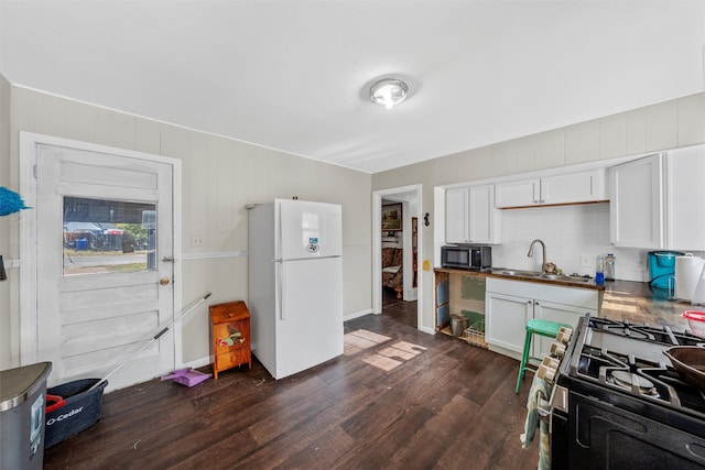 kitchen featuring dark wood-type flooring, white cabinets, sink, gas range oven, and white fridge