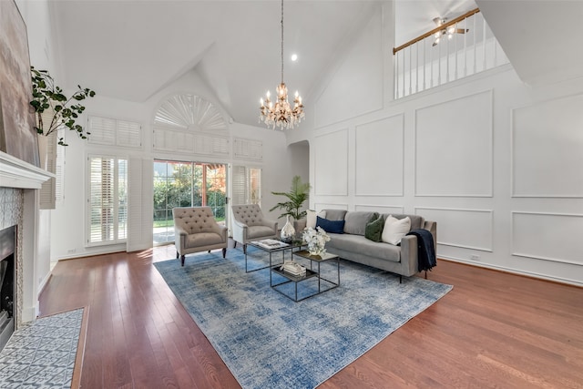 living room featuring hardwood / wood-style flooring, a fireplace, high vaulted ceiling, and an inviting chandelier