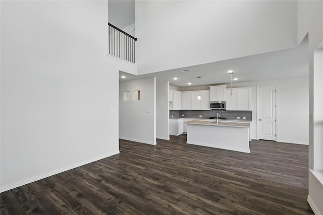 5036 Water Lily Ln, Fort Worth, TX 76036 - kitchen with dark wood-type flooring, a kitchen island with sink, stainless steel microwave, tasteful backsplash, and baseboards