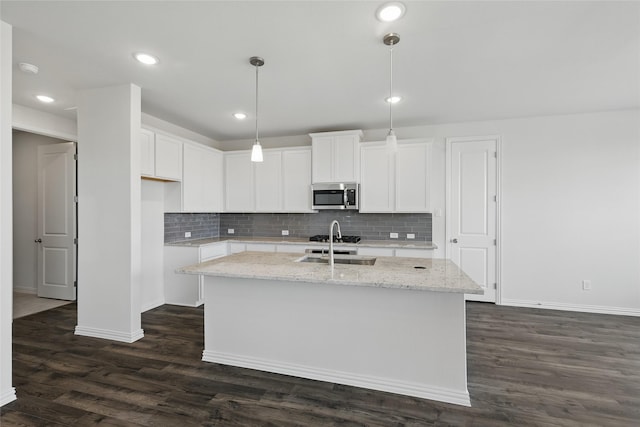 5036 Water Lily Ln, Fort Worth, TX 76036 - kitchen featuring light stone counters, stainless steel microwave, dark wood-type flooring, and a center island with sink