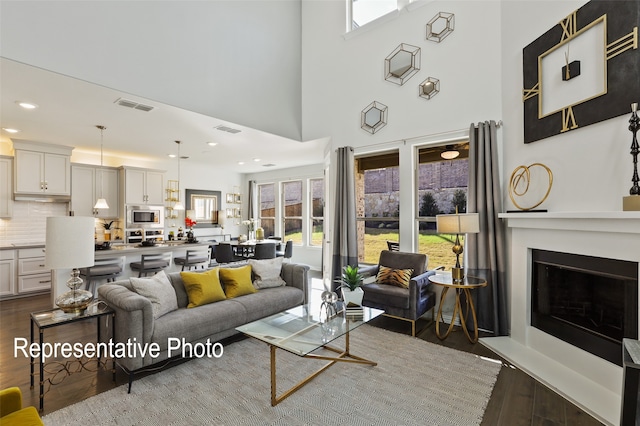 living room featuring a towering ceiling and dark wood-type flooring