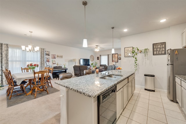 kitchen featuring sink, decorative light fixtures, black dishwasher, stainless steel refrigerator, and an island with sink