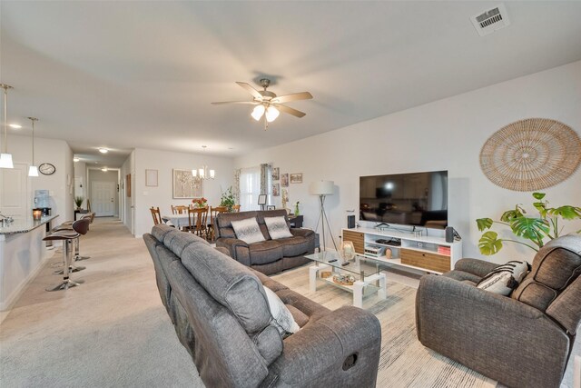 carpeted living room with ceiling fan with notable chandelier