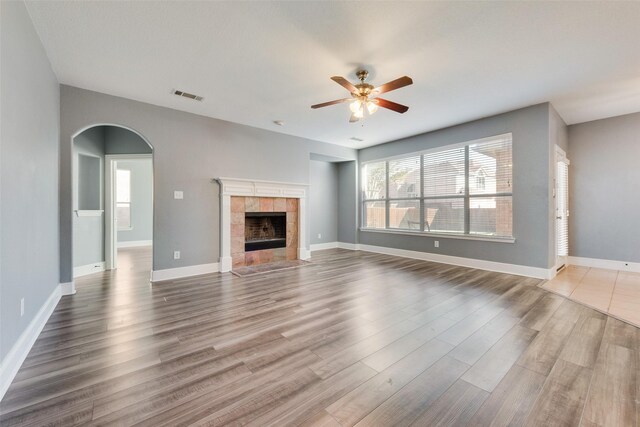 unfurnished living room featuring a tile fireplace, ceiling fan, and hardwood / wood-style floors