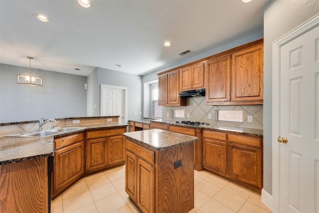 kitchen featuring pendant lighting, stainless steel gas stovetop, sink, light tile patterned floors, and a kitchen island