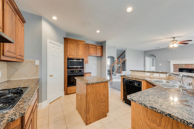 kitchen featuring ceiling fan, sink, black appliances, light tile patterned floors, and a center island