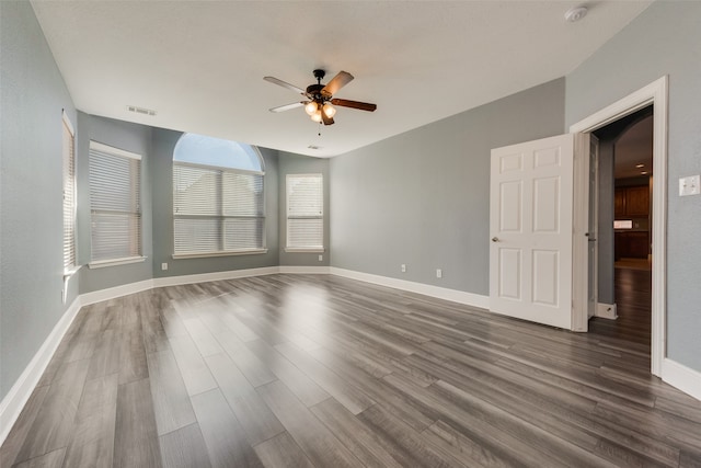 empty room with dark hardwood / wood-style floors and ceiling fan