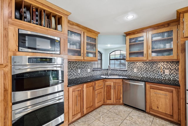 kitchen with stainless steel appliances, tasteful backsplash, sink, and dark stone countertops