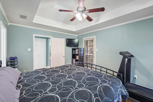 carpeted bedroom with a raised ceiling, crown molding, and ceiling fan