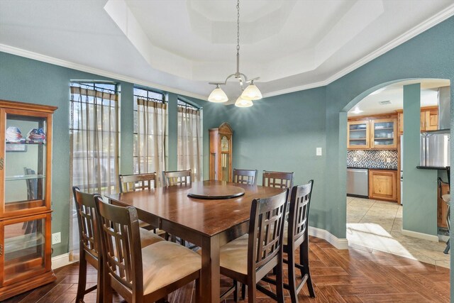 dining area with a tray ceiling, dark parquet floors, and a chandelier