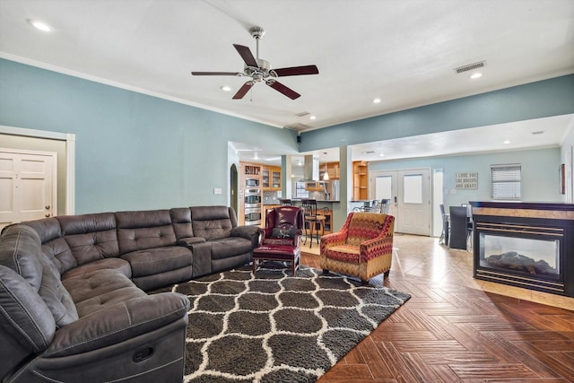 living room featuring parquet floors, ornamental molding, ceiling fan, and a multi sided fireplace