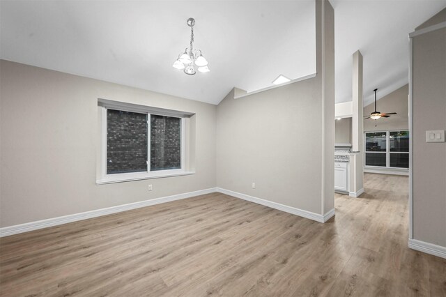 spare room featuring ceiling fan with notable chandelier, lofted ceiling, and light wood-type flooring