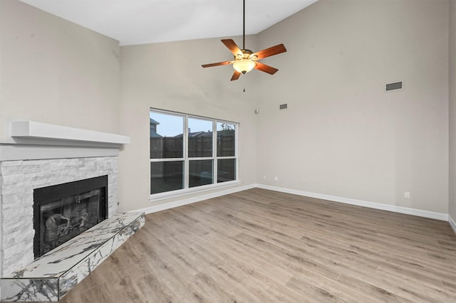 unfurnished living room featuring a fireplace, light hardwood / wood-style flooring, high vaulted ceiling, and ceiling fan