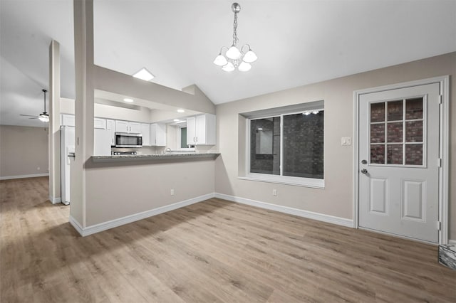 kitchen featuring kitchen peninsula, light wood-type flooring, decorative light fixtures, white cabinetry, and lofted ceiling