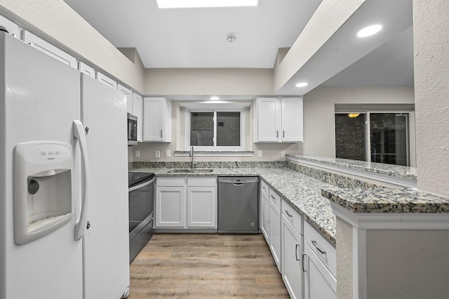 kitchen with white cabinets, appliances with stainless steel finishes, stone counters, and sink