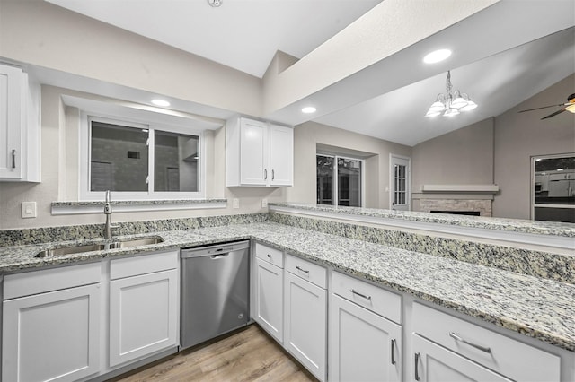 kitchen featuring white cabinetry, dishwasher, sink, vaulted ceiling, and ceiling fan with notable chandelier