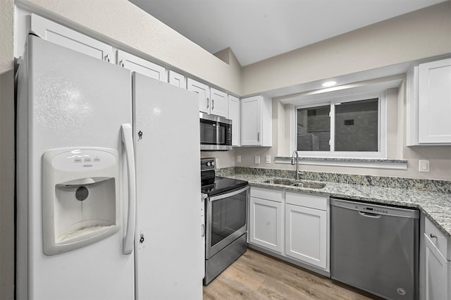 kitchen with white cabinets, stainless steel appliances, light stone counters, and sink