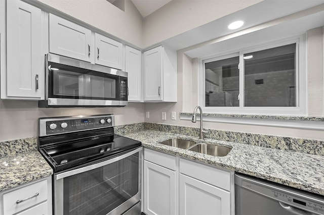 kitchen featuring appliances with stainless steel finishes, light stone counters, white cabinetry, and sink