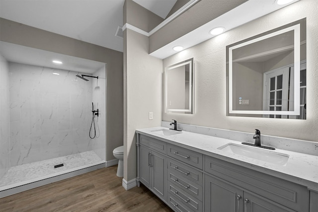 bathroom featuring tiled shower, vanity, hardwood / wood-style flooring, and toilet