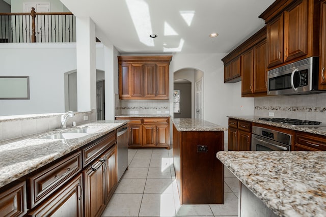 kitchen featuring tasteful backsplash, light stone counters, stainless steel appliances, sink, and light tile patterned floors