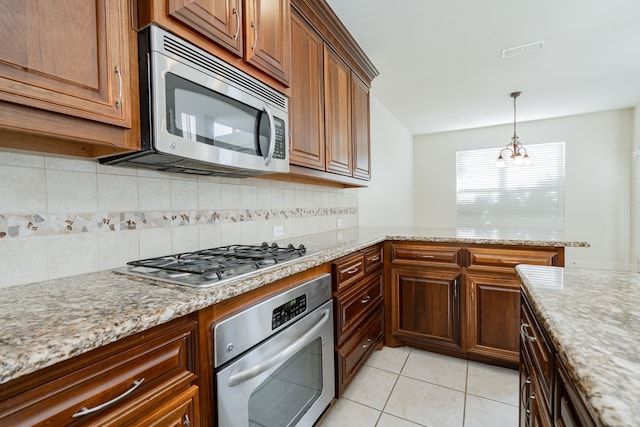 kitchen with light stone countertops, light tile patterned floors, stainless steel appliances, and an inviting chandelier