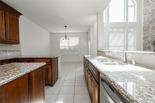 kitchen featuring light tile patterned flooring, light stone countertops, a notable chandelier, and sink