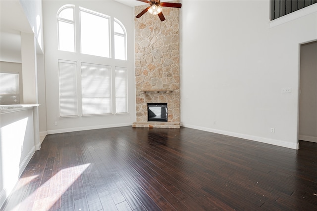 unfurnished living room with dark wood-type flooring, a towering ceiling, and a healthy amount of sunlight