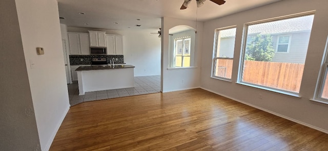 unfurnished living room featuring sink, ceiling fan, and light hardwood / wood-style flooring