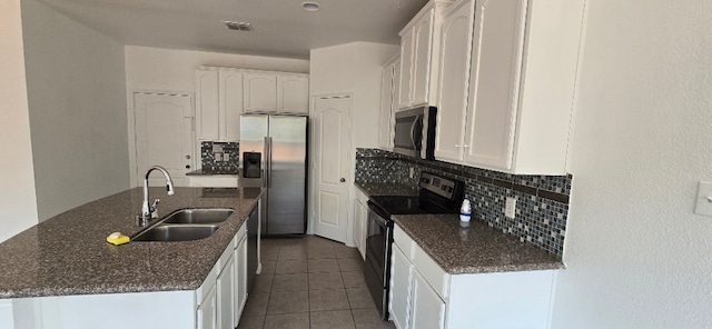 kitchen with sink, stainless steel appliances, a kitchen island with sink, decorative backsplash, and white cabinets