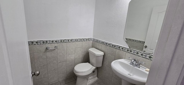 bathroom with tile walls, sink, and toilet