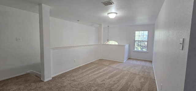 unfurnished room featuring light colored carpet and a textured ceiling