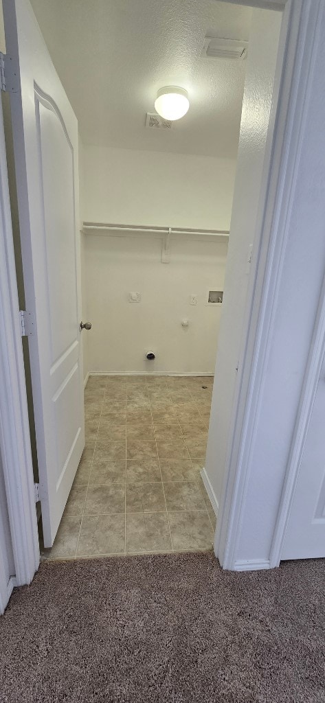 washroom featuring electric dryer hookup, light carpet, and a textured ceiling