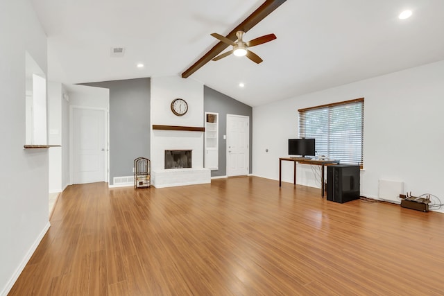 unfurnished living room with lofted ceiling with beams, light hardwood / wood-style floors, a brick fireplace, and ceiling fan