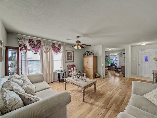 living room featuring ceiling fan, light hardwood / wood-style floors, and a textured ceiling