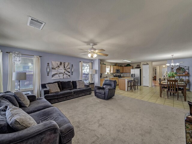 living room featuring ceiling fan with notable chandelier, light tile patterned floors, a textured ceiling, and a wealth of natural light