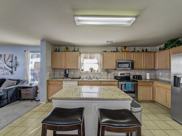 kitchen with decorative backsplash, sink, a center island, and stainless steel appliances