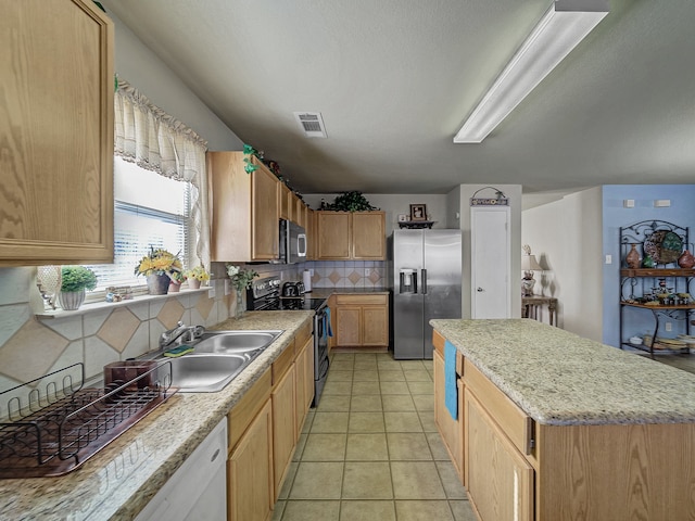 kitchen featuring a center island, sink, decorative backsplash, light tile patterned floors, and stainless steel appliances